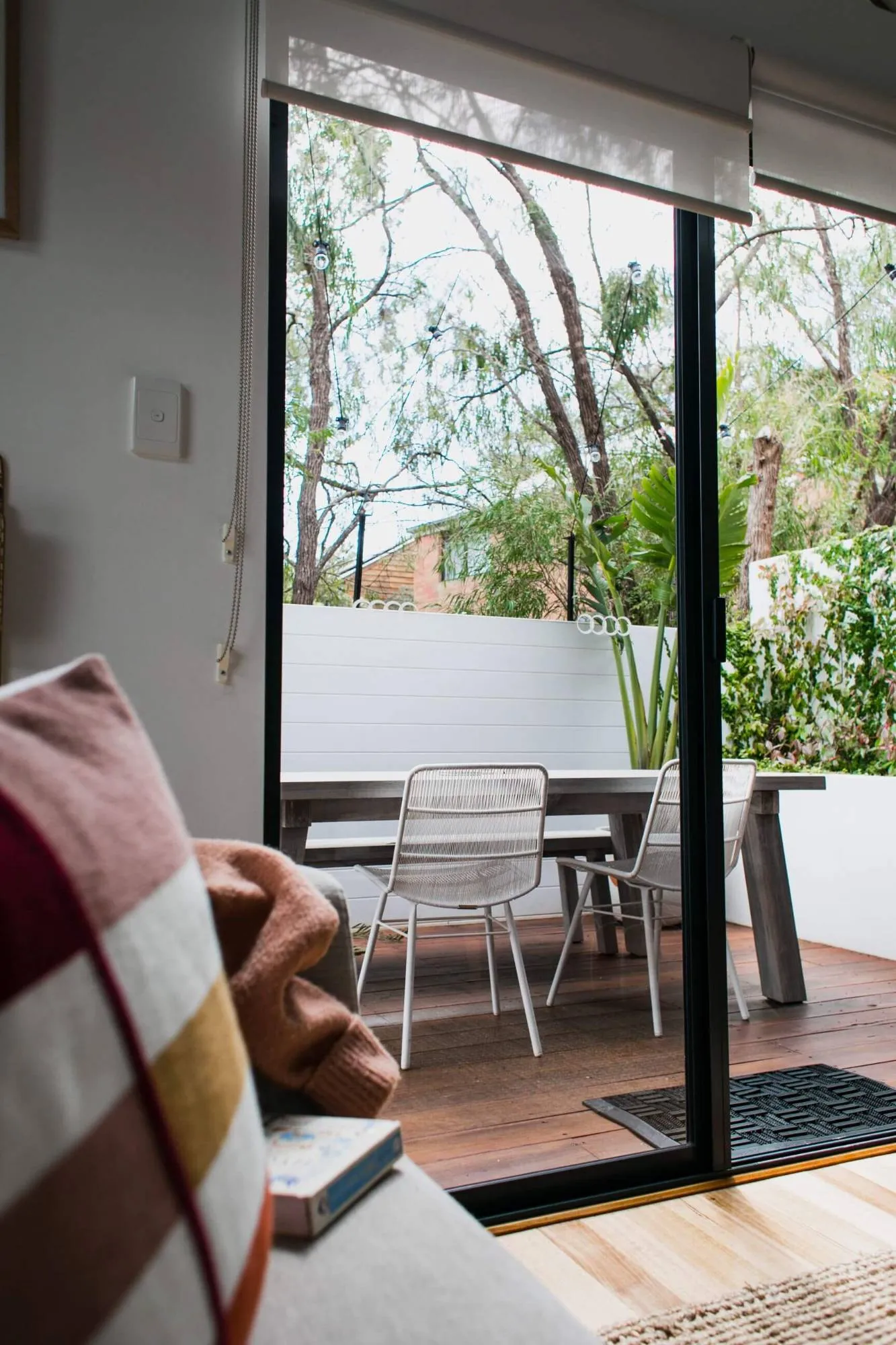 View from the sofa through clean glass doors to a timber deck and garden